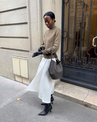 woman in turtleneck, white skirt, and gloves