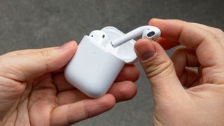 Person som holder AirPods og et ladeetui