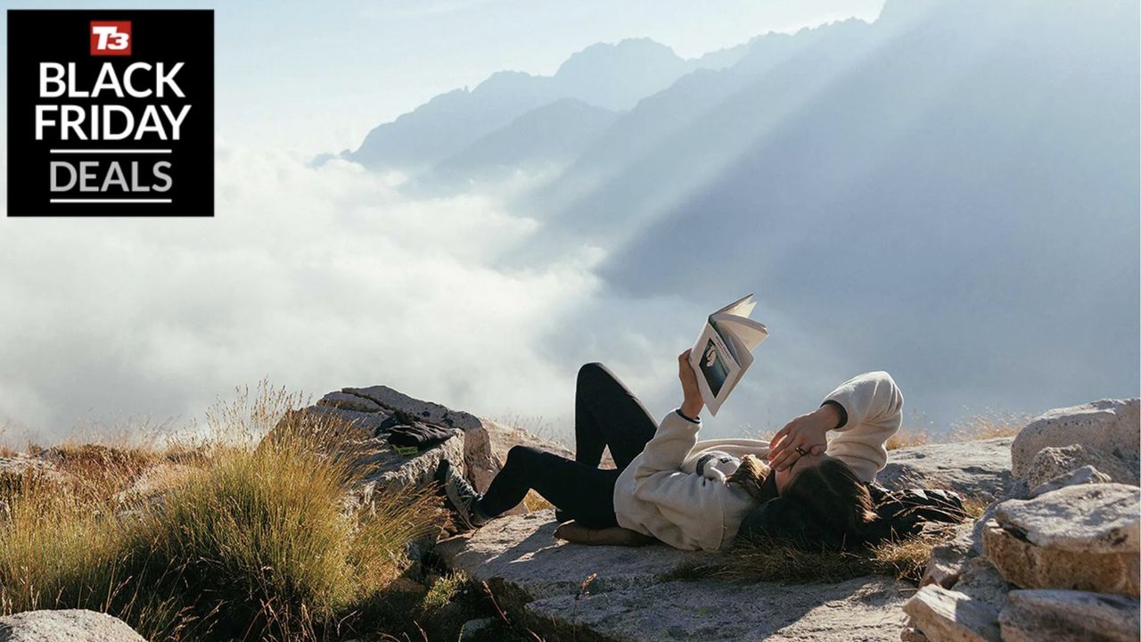 Woman wearing Patagonia reading a book on top of a mountain