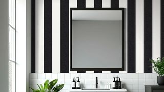 A bathroom decorated with Awning Stripe Wallpaper - Monochrome - Woodchip & Magnolia. the image shows a window to the left and a large mirror on the striped wallpaper.