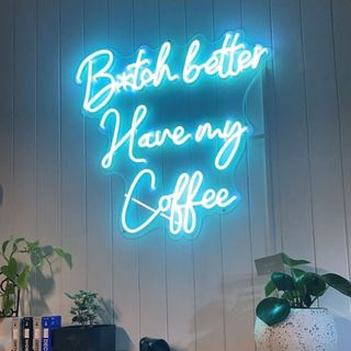 blue neon coffee sign in a tiled kitchen with plants