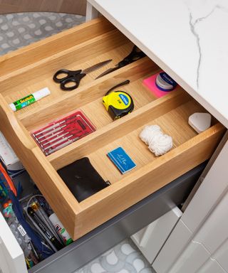 image of open junk drawer showing scissors, glue, small screwdriver set, thread, phone charger