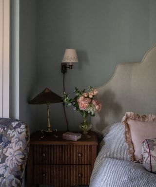 bedroom with gray-green walls and nightstand with flowers