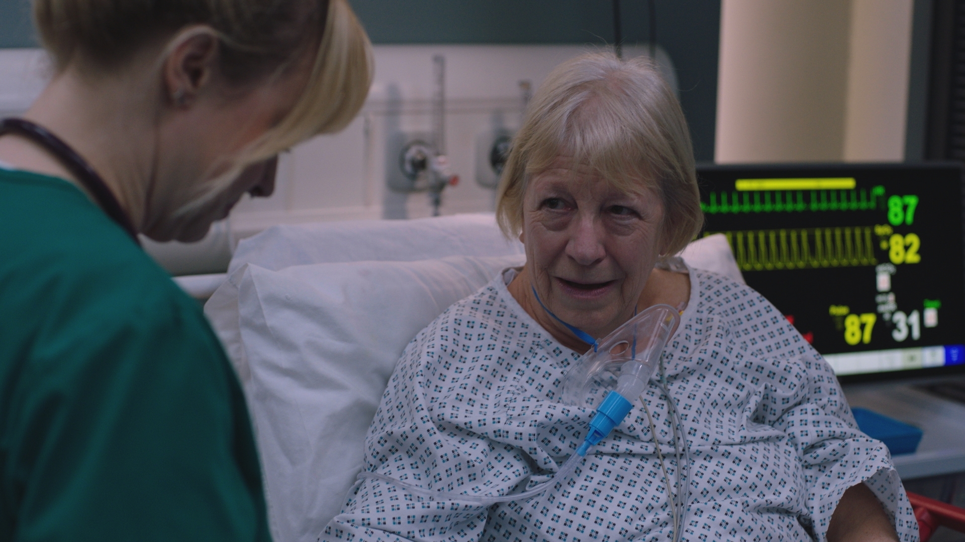 Sandra Maitland as patient Maggie smiling at Nicole, as the doctor treats her.