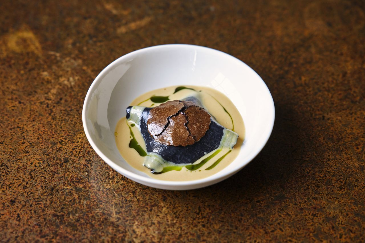 A plant-based restaurant's dishes feature greens and vegan ingredients assembled into visually striking, earthy plates served in white dishes against textural surfaces.