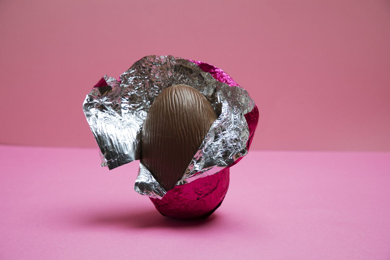 A half unwrapped Easter egg on a pink background