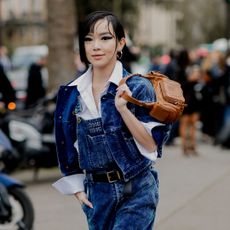 a woman at fashion week wearing overalls and a jean jacket