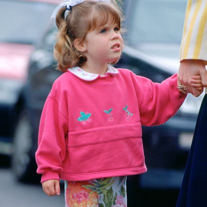 Princess Eugenie holds hands with mom Sarah Ferguson in June 1994, while wearing floral leggings and a pink sweatshirt, showing she's a royal style inspiration for Princess Lilibet