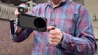 NEEWER PA024K Cage for iPhone 15 Pro Max held in the hands of DCW reviewer George Cairns