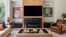 A living room with a TV installed above a fireplace, with the entire unit made in wood veneer