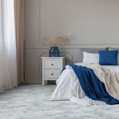 blue and white bedroom with pale blue patterned carpet and white and blue bedlinen