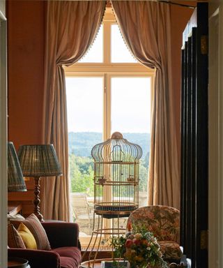 traditional living space with an ornate vintage bird cage and draped curtains