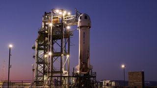 A white Blue Origin suborbital rocket stands on its launch pad at dusk in West Texas.