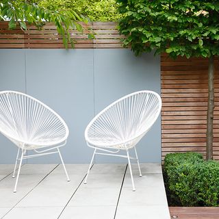 raised terrace with painted panel and white metal frame chairs