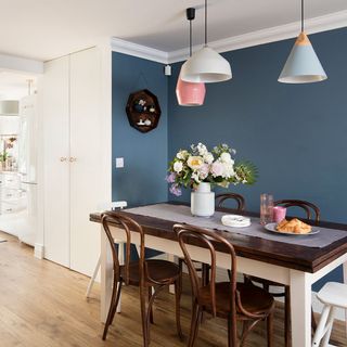 dining room with blue wall dinning table and chairs white cupboard and wooden flooring
