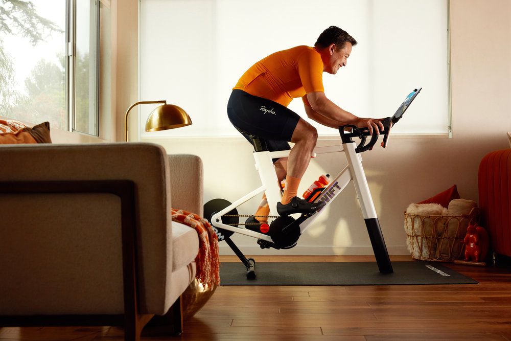 A man rides a Zwift Ride smart trainer in a living room