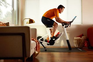 A man rides a Zwift Ride smart trainer in a living room