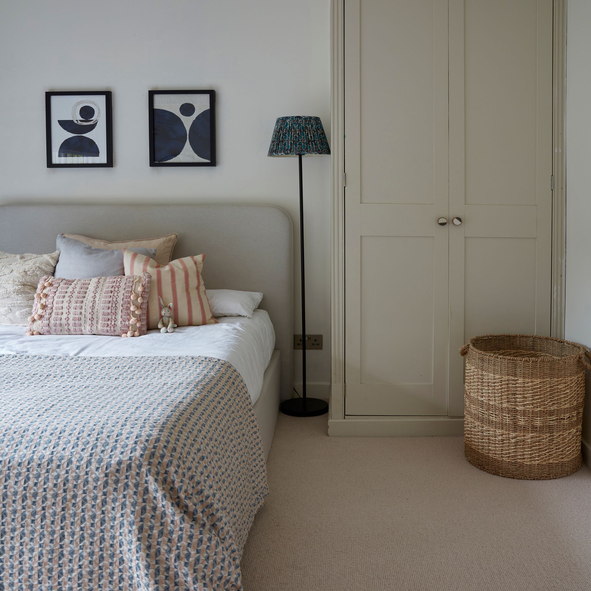 Neutral painted bedroom with white walls, white and beige bedding and a beige painted wardrobe next to the bed