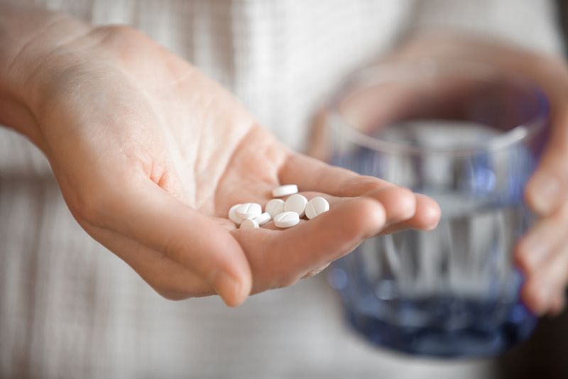 A person holds a handful of pills.