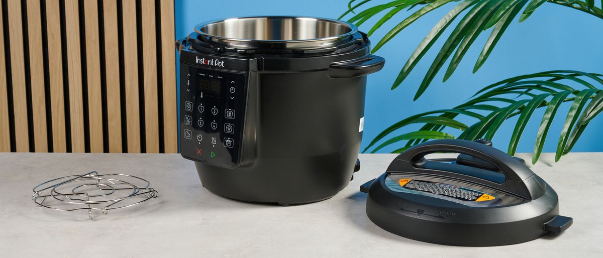 a black pressure cooker photographed against a blue background, showing its cooking presets, steam release valve, and Instant Pot branding