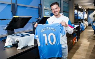 Manchester City midfielder Jack Grealish holding a shirt printed with his name and number in the club shop