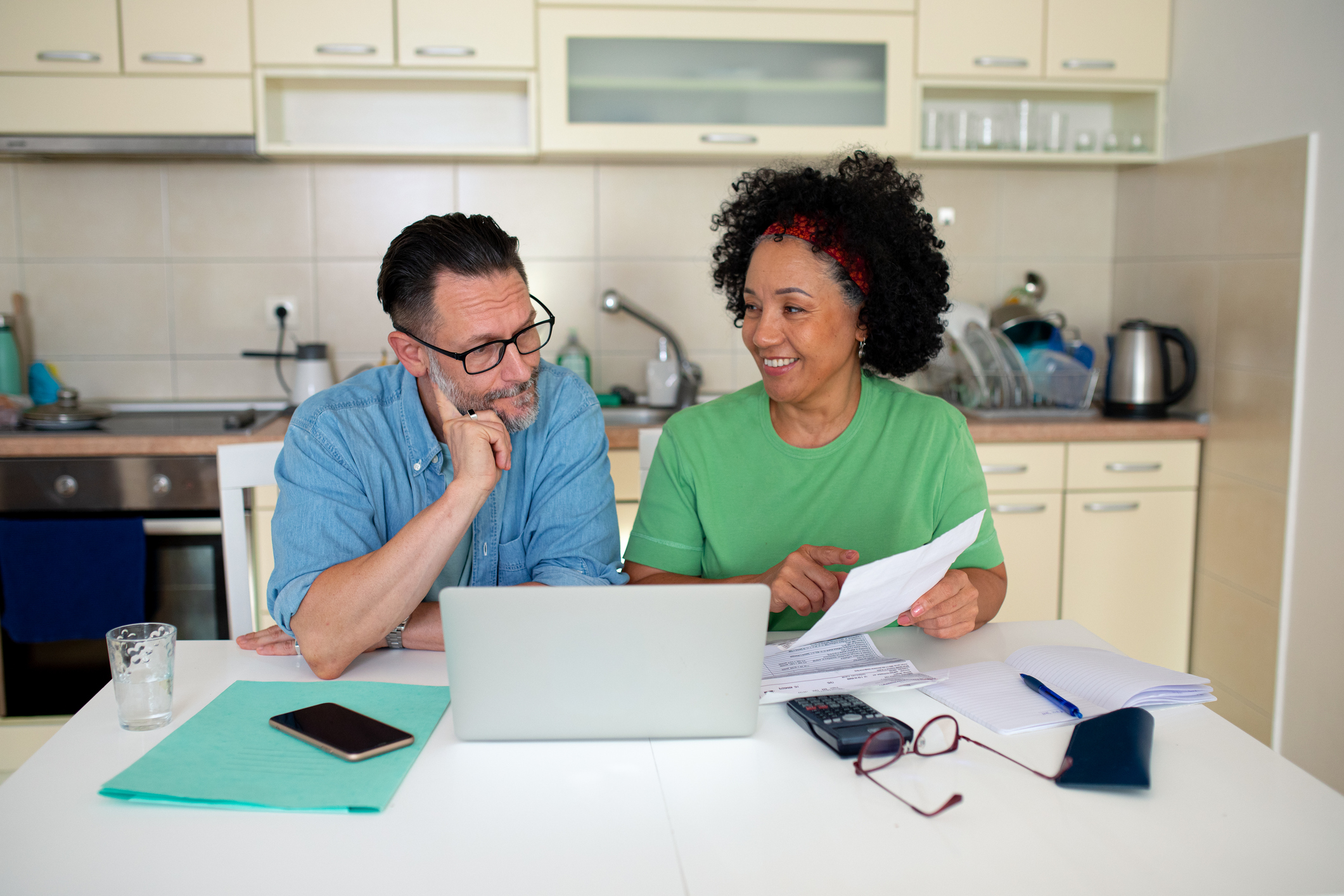 Mature couple discussing bills and income, using laptop for financial planning