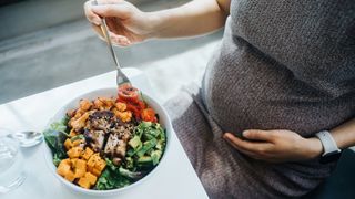 pregnant woman eating a healthy salad bowl