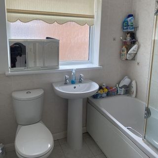 A plain white bathroom with bath, sink and toilet