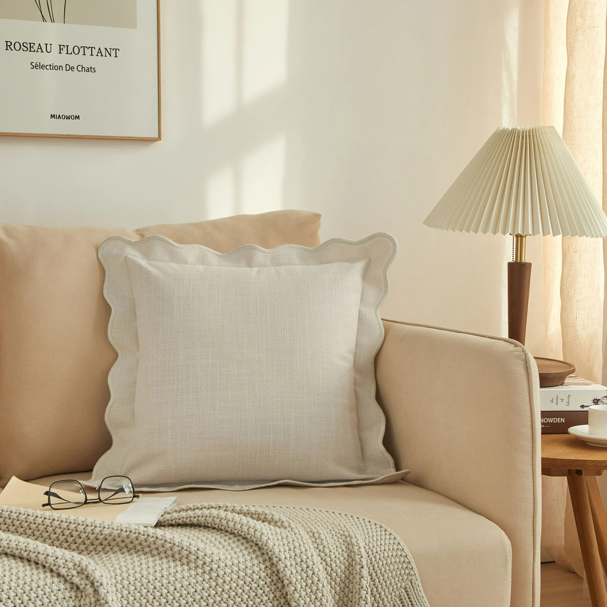 A beige throw pillow with scalloped detailing on a neutral couch