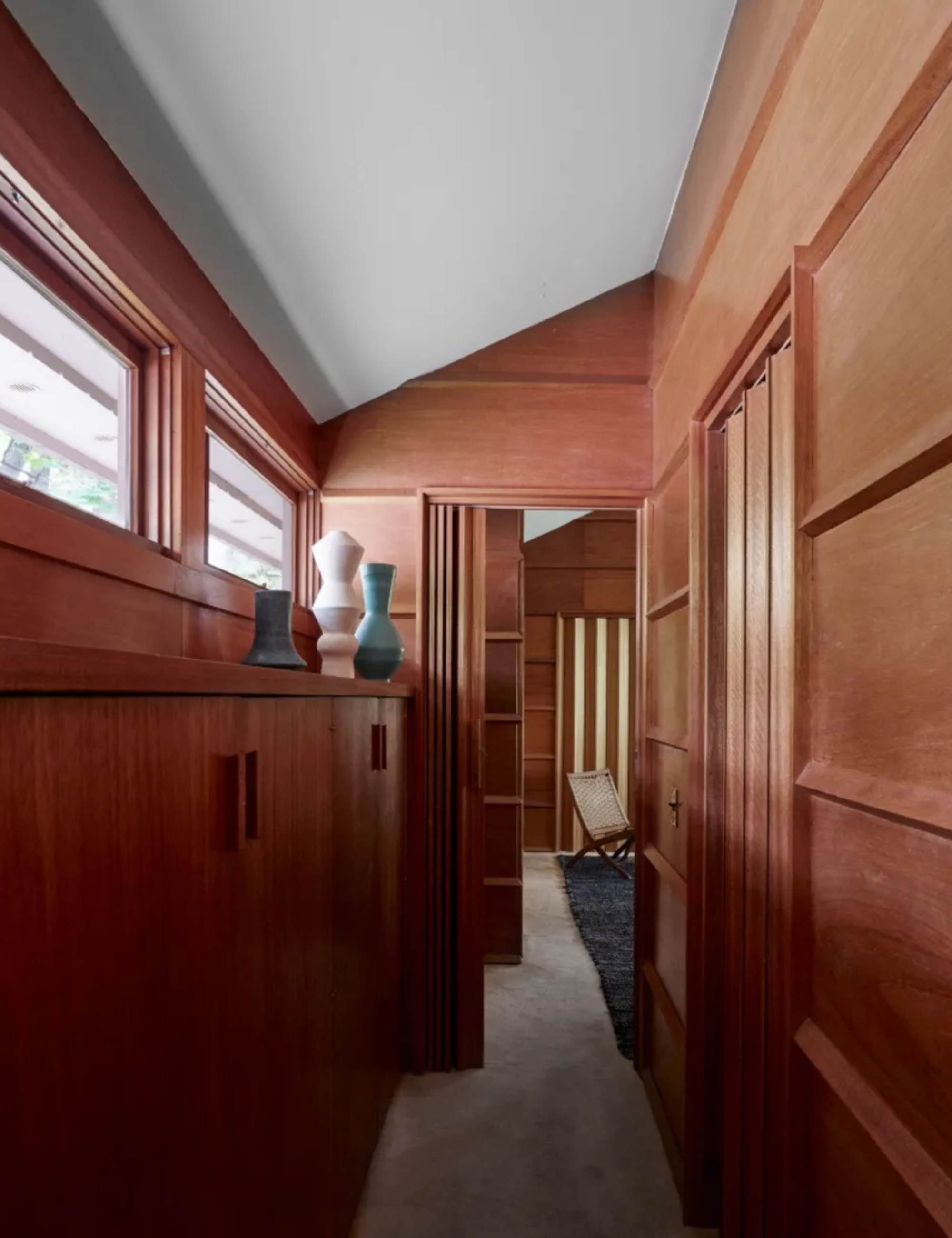 Wood panelled hallway with vases and cabinets