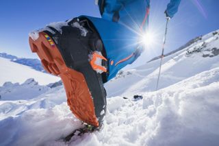 A close up of a ski boot walking up a snowy incline