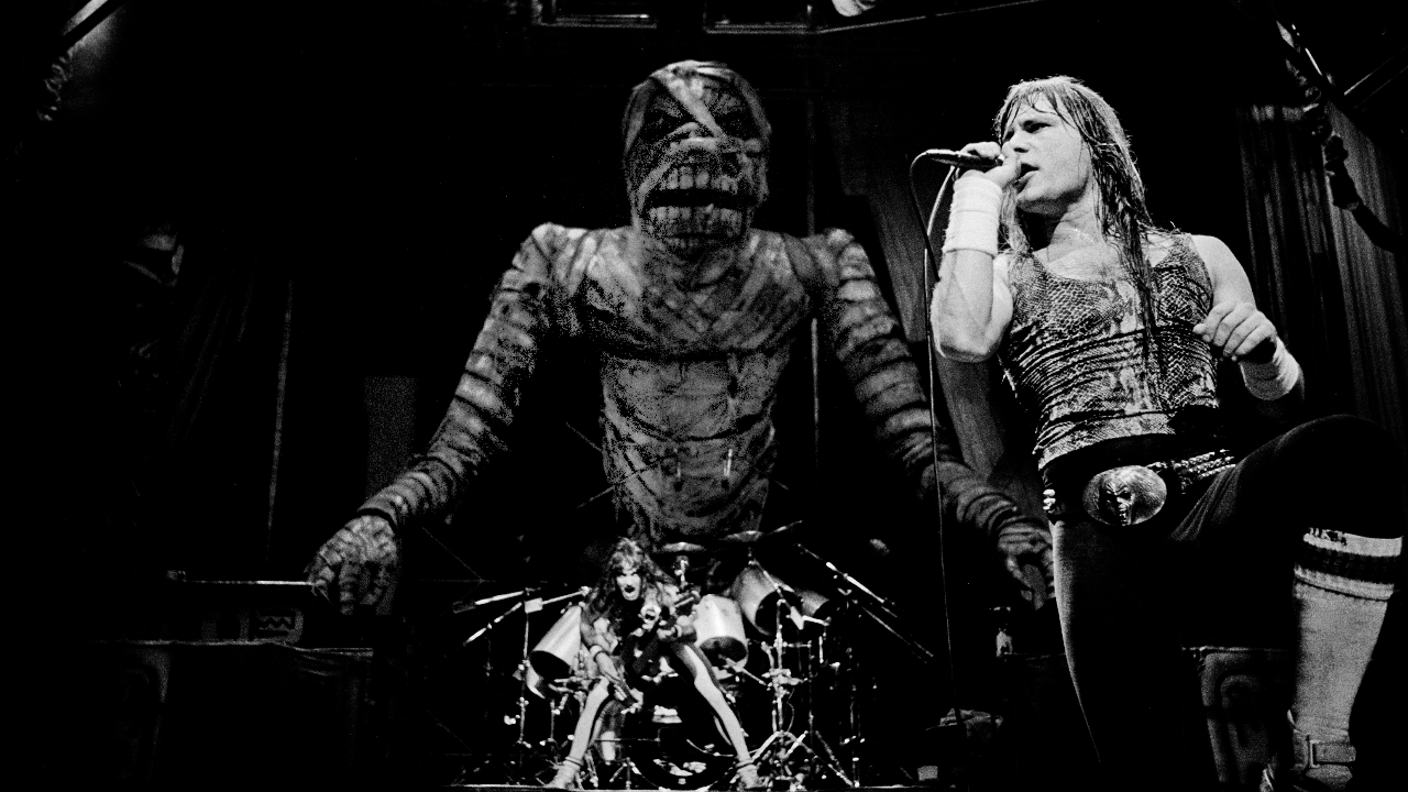 Bruce Dickinson on stage singing as mummy Eddie leers over him