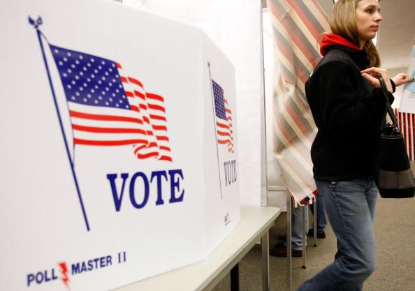 A woman leaves a voting booth.