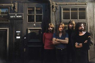 Pink Floyd standing against a wall