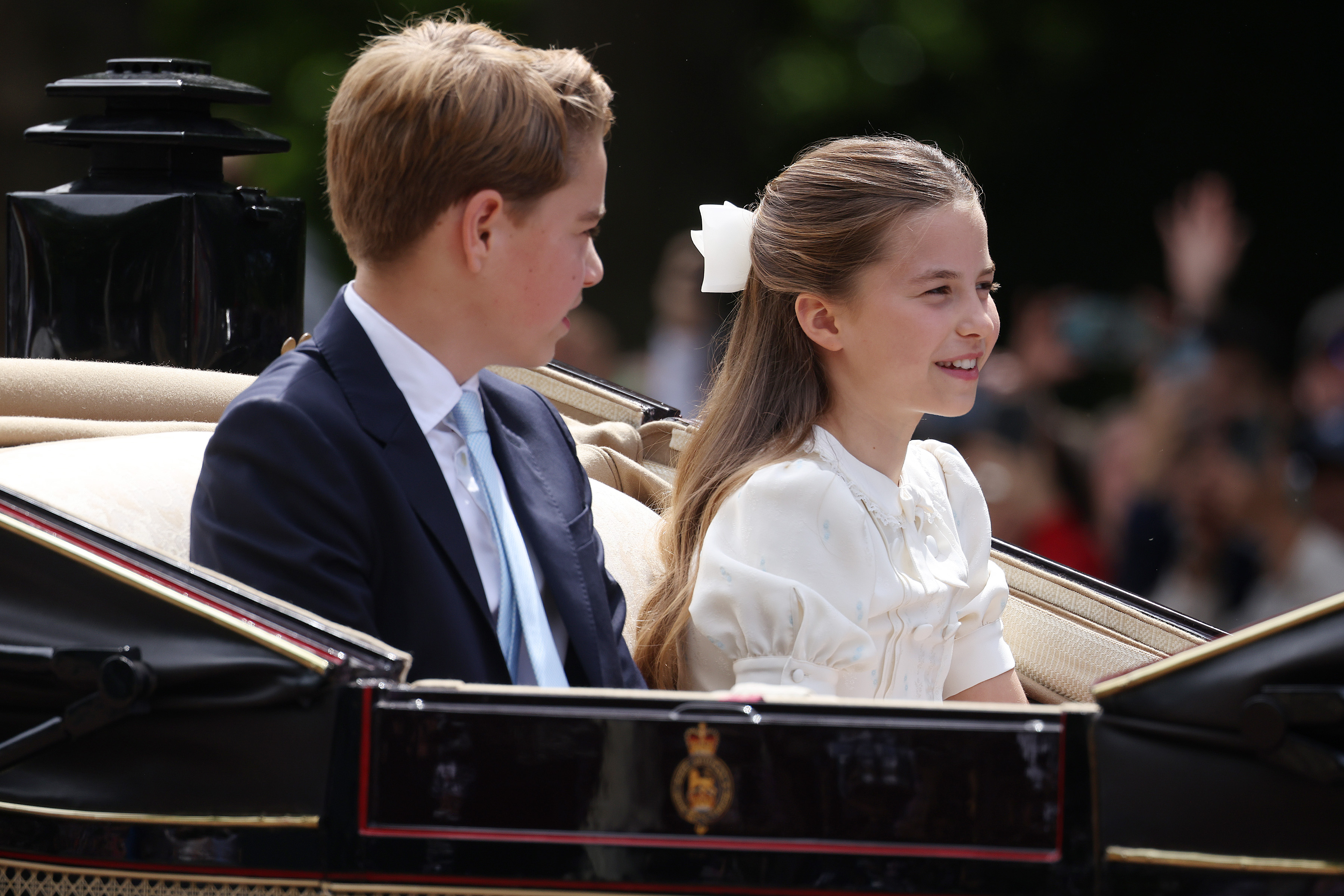 Princess Charlotte wears a white bow in her hair for Trooping the Colour 2026 and sits next to brother Prince George, who wears a suit