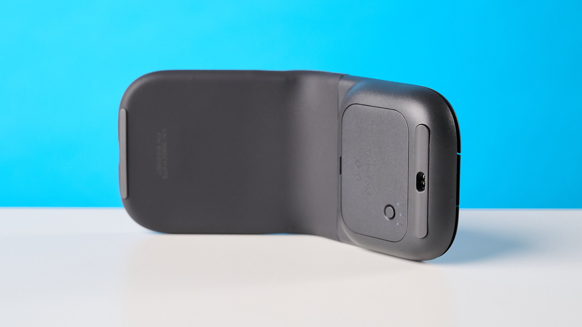 Logitech Mobi Fold mouse in graphite photographed in front of a blue background