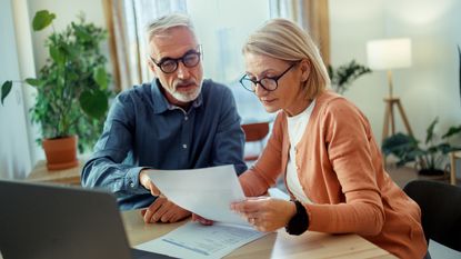 An older couple work on financial planning together at their kitchen table.