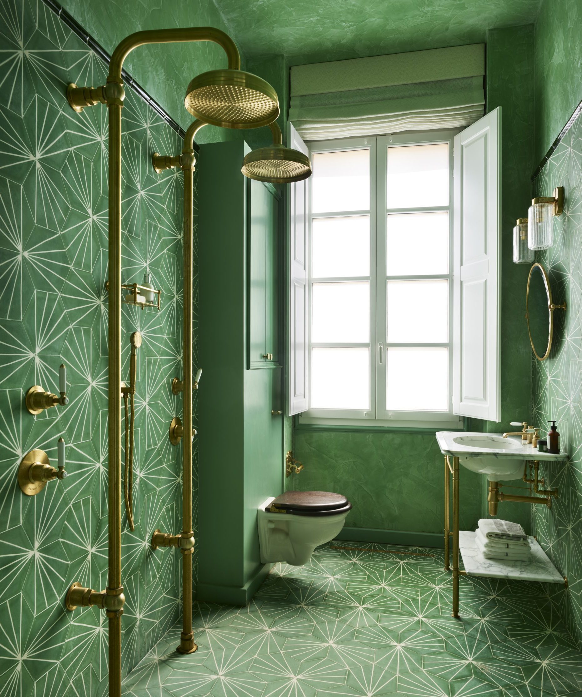 A green shower room with gold and green patterned tiles and a traditional style toilet