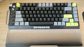 A black and green NuPhy Field75 keyboard on a wooden desk