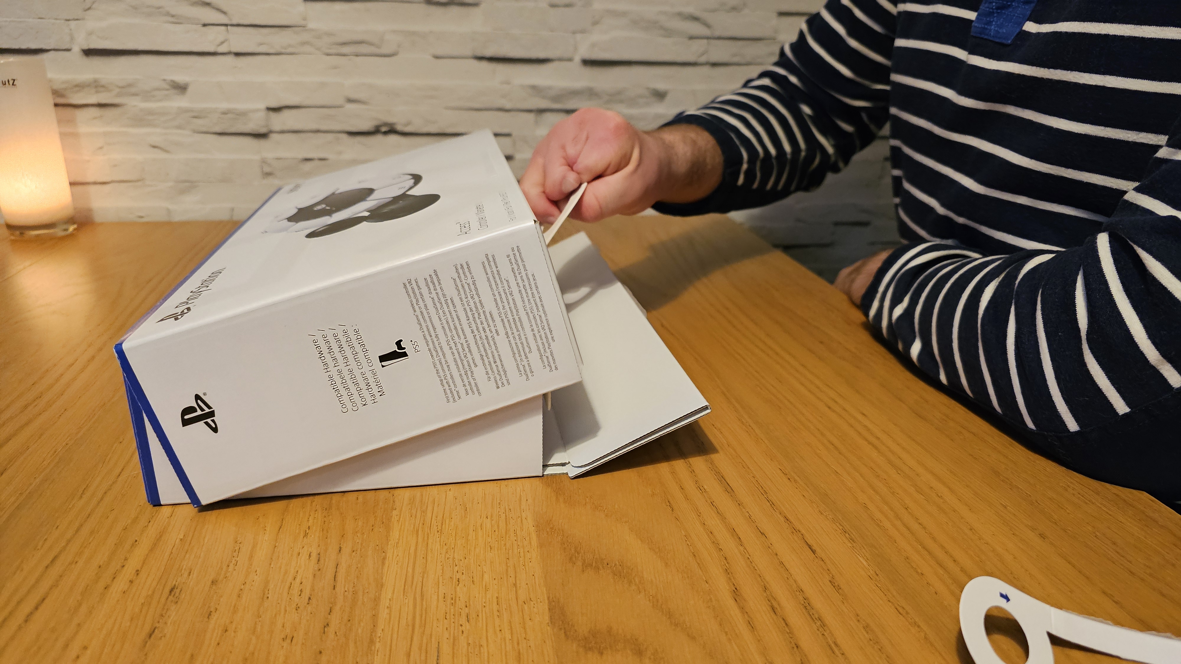 Unboxing the PlayStation Access controller with one hand on a wooden surface