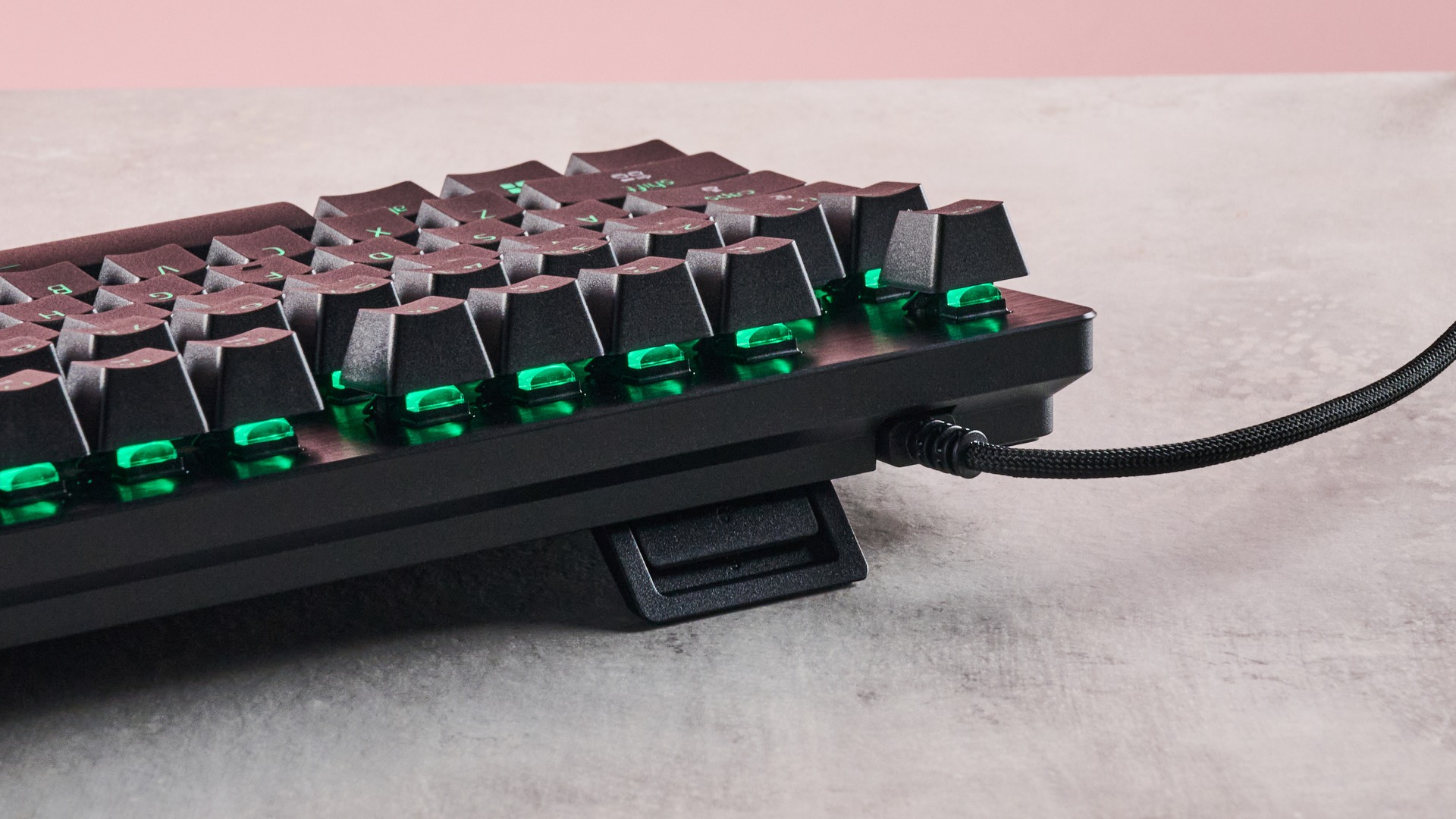 Back view of Razer Huntsman V3 Tenkeyless 8KHz with green RGB lighting visible underneath keycaps, on a desk