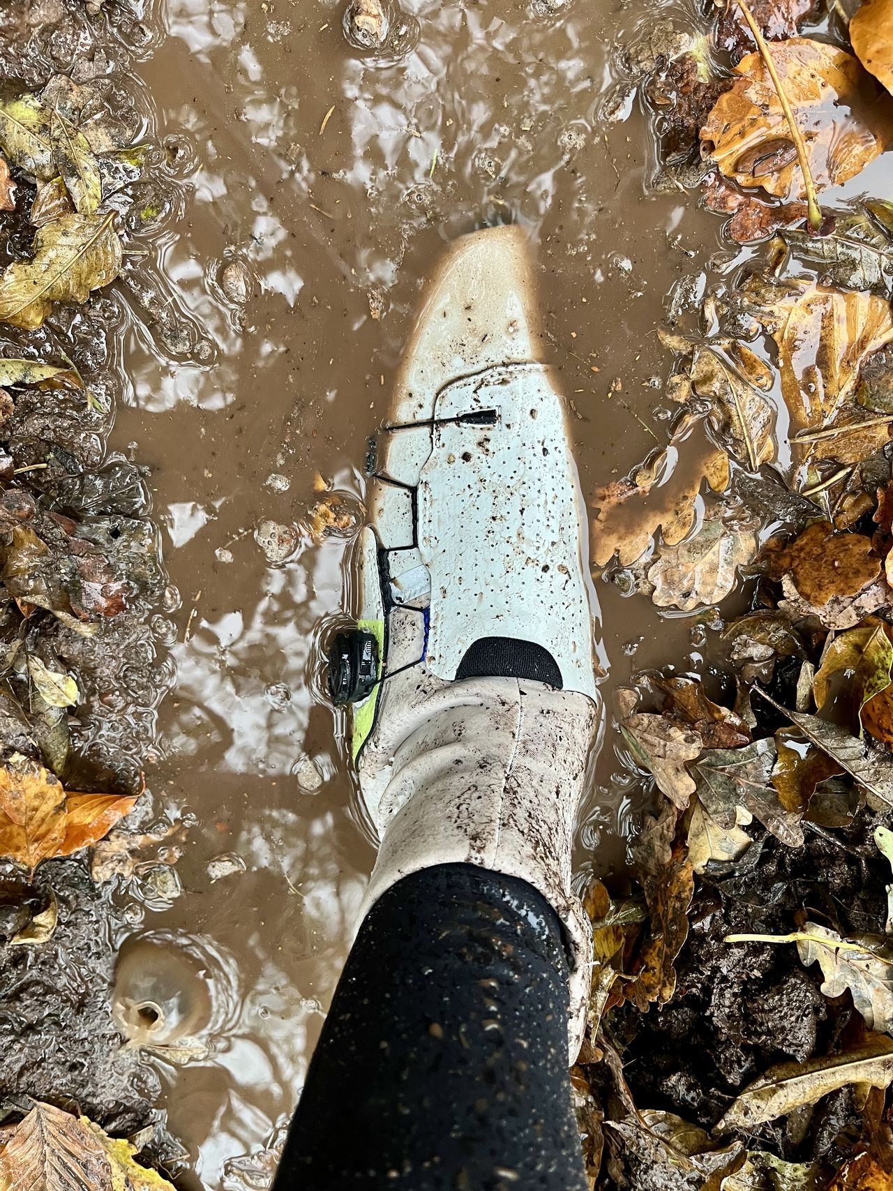 A cyclists foot submerged in a muddy puddle