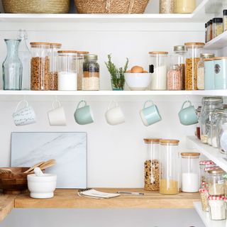 kitchen with white wall shelf with jars cups and bowl