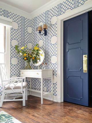 Blue painted double doors with trim in wallpapered room