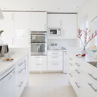 kitchen with white wall and wall mounted white cabinet and microwave and biscuits