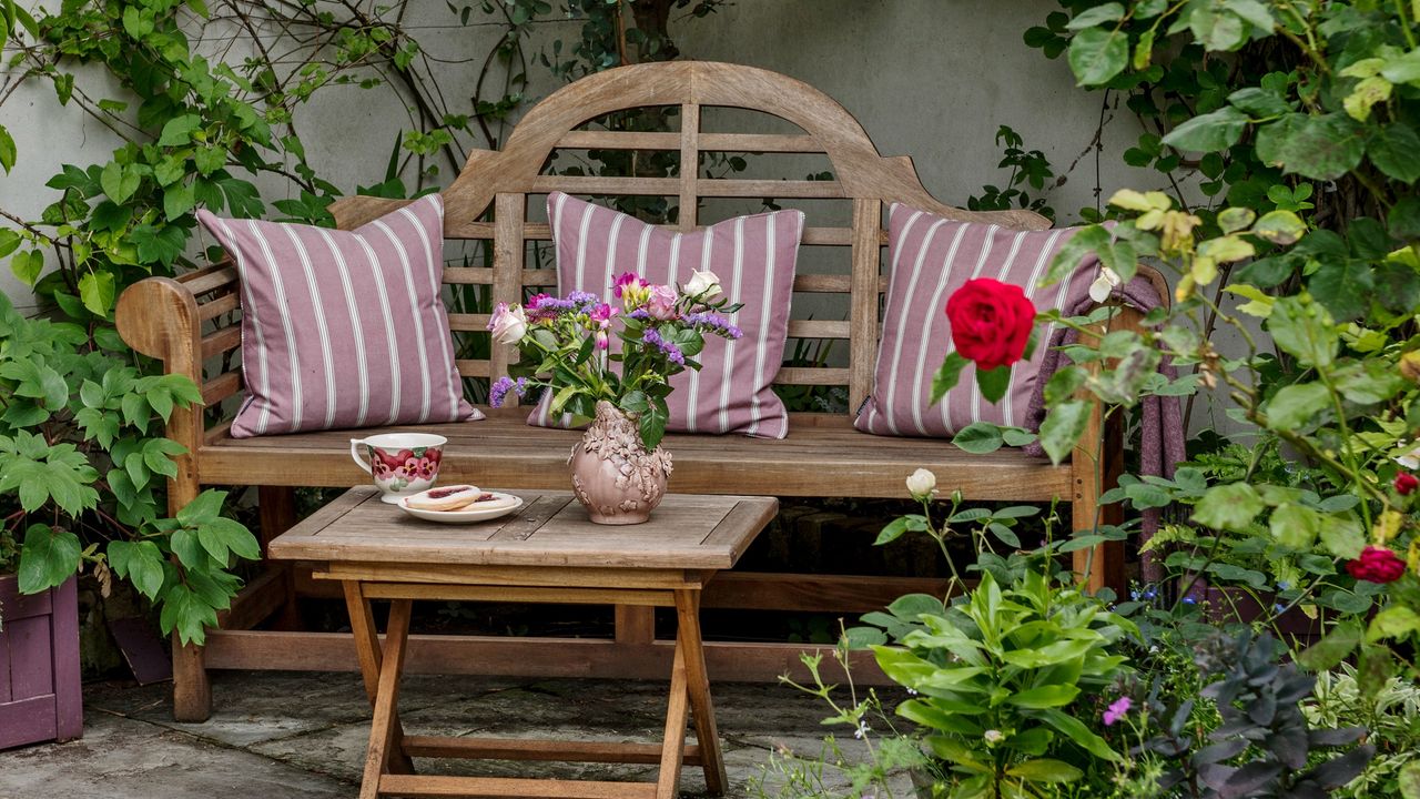 A garden bench with a table and cushions