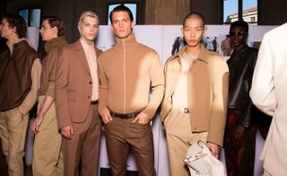 Three male models wearing clothing by Salvatore Ferragamo in shades of brown.
