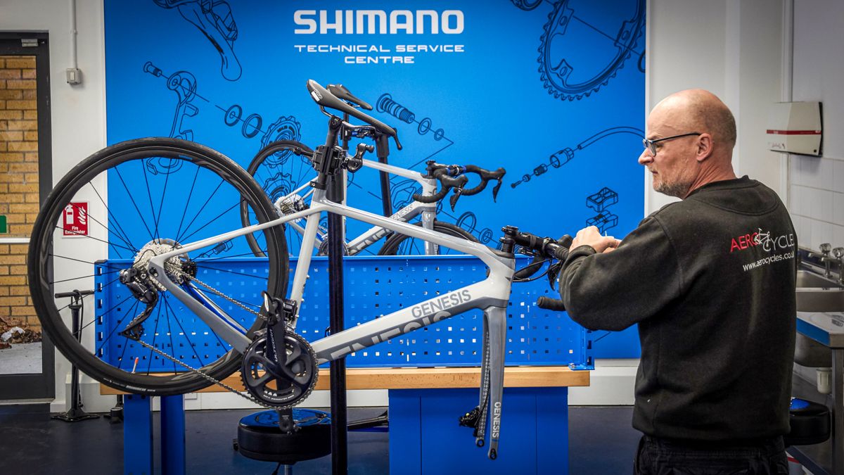 a mechanic works on a Genesis bike in a Shimano workshop