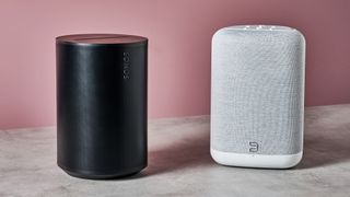 The Sonos Era 100 on the left and the Bluesound Pulse Flex on the right in front of a pink background.