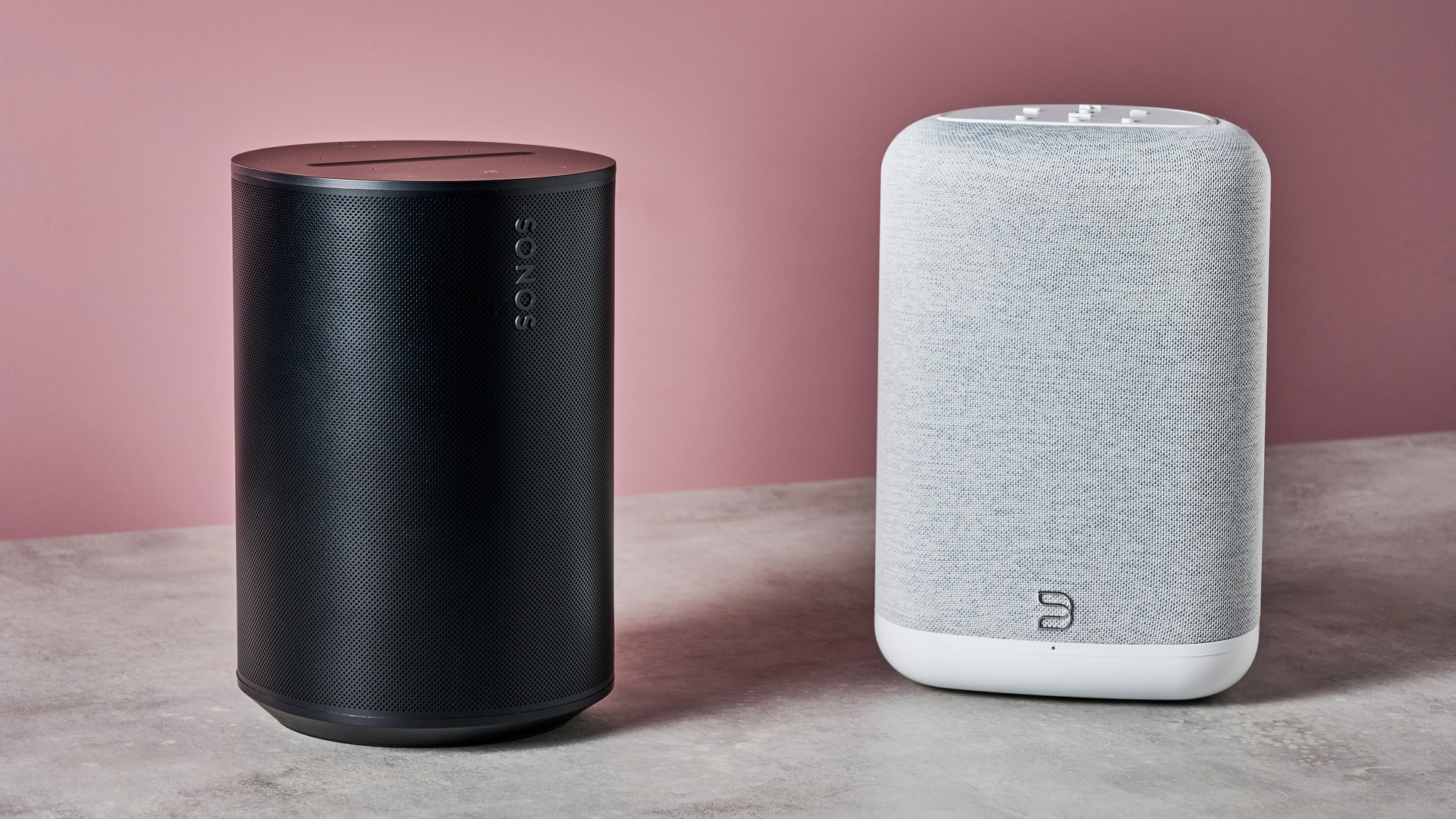 The Sonos Era 100 on the left and the Bluesound Pulse Flex on the right in front of a pink background.